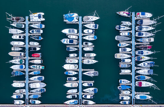 Aerial view of yachts at sea docked in the marina with rows of boats moored along the piers in Herzliya, Tel Aviv District, Israel.