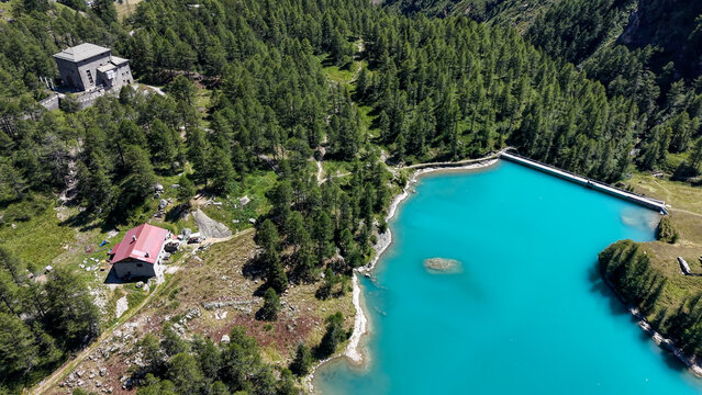 Aerial view of the Palu Hydroelectric Power Plant surrounded by dense pine forests and the turquoise waters of the reservoir in Poschiavo, Grisons, Switzerland.