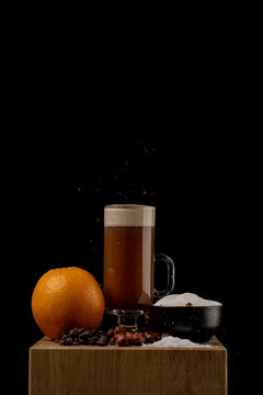 View of a coffee drink in a glass with an orange, coffee beans, hazelnuts, and sugar on a wooden block in Norway.