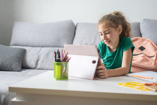 Smiling schoolgirl using tablet for online learning at home