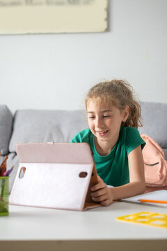 Smiling schoolgirl using tablet for online learning at home