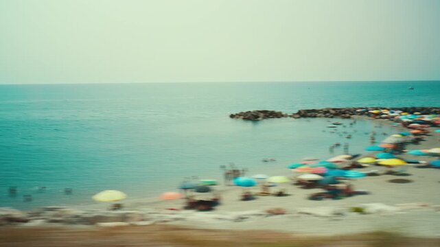 Tourists swimming in the sea in Calabria, seen from a train window