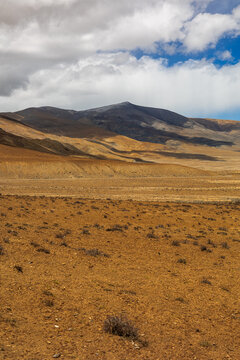 View of the arid landscape and rugged mountains surrounding the high-altitude Peiku Cuo alpine lake in Shigatse, Tibet, China.