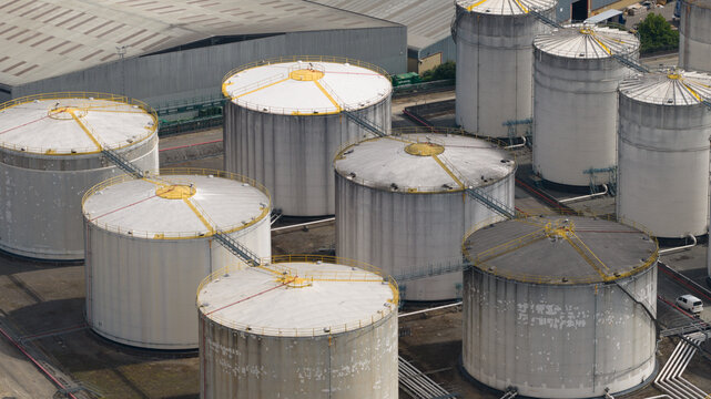 Aerial view of Navigator Terminals Thames featuring large cylindrical industrial storage tanks with metal walkways and piping systems in Grays, England, United Kingdom.
