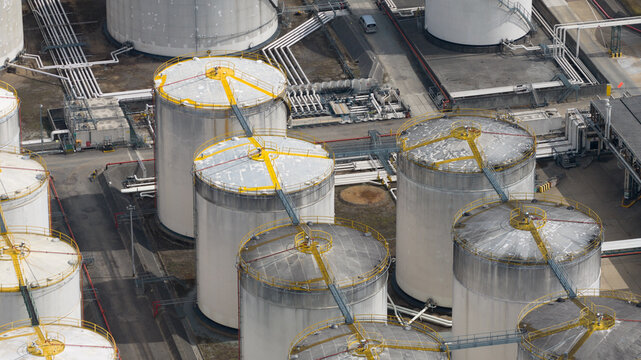 Aerial view of Navigator Terminals Thames featuring large industrial storage tanks with yellow access walkways and complex piping networks in Grays, England, United Kingdom.