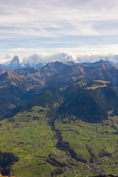 Aerial view of the Niesen Hiking View Point overlooking the green valley, rolling hills, and snow-capped peaks of the Swiss Alps in Reichenbach im Kandertal, Canton of Bern, Switzerland.