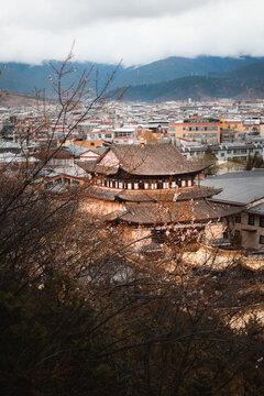 View of the traditional temple in Shangri-La City with layered tiled roofs, surrounded by urban buildings and distant mountains in Diqing Tibetan Autonomous Prefecture, Yunnan, China.
