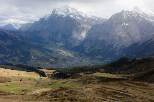View of Kleine Scheidegg with alpine meadows, winding paths, and snow-capped peaks in the background in Lauterbrunnen, Canton of Bern, Switzerland.