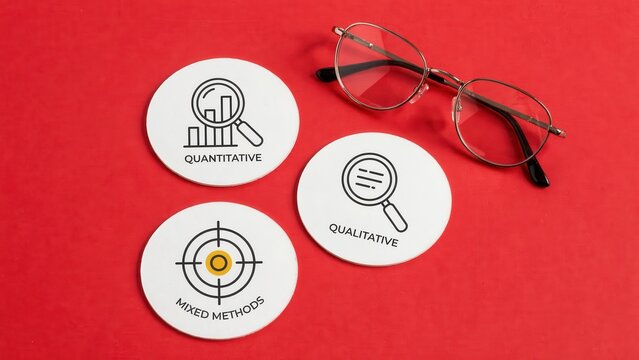 Three round paper coasters with icons and text for quantitative, qualitative, and mixed methods research next to eyeglasses on a red background