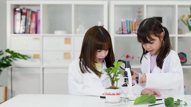 Asian Elementary Students in Lab Coats Studying Biology with Microscope