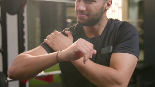 Confused African American man male athlete suffering shoulder pain in gym after workout upset sportsman holding injured arm cramp ache and discomfort following failed fitness exercise recovery indoors