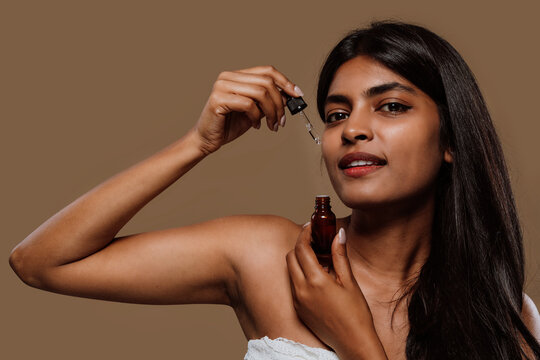 Young woman applying serum on her face