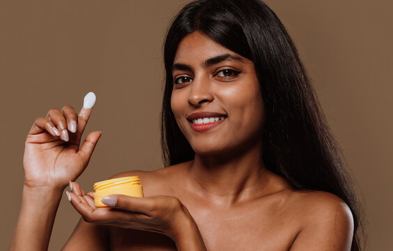  Young woman applying moisturizer on face