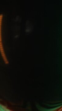 Portrait of teen boy wearing creepy clown makeup, smiling maliciously while holding black balloon. Footage is ideal for Halloween event promos and horror content, vertical