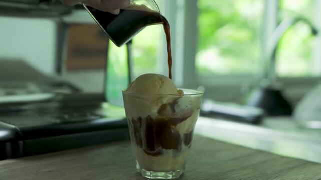 Italian Affogato of hand pouring espresso into vanilla ice cream, blending bitter and sweet flavours into a creamy, aromatic dessert drink.