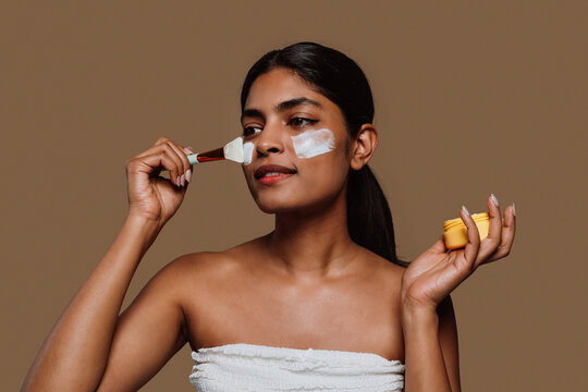  Young woman applying moisturizer on face