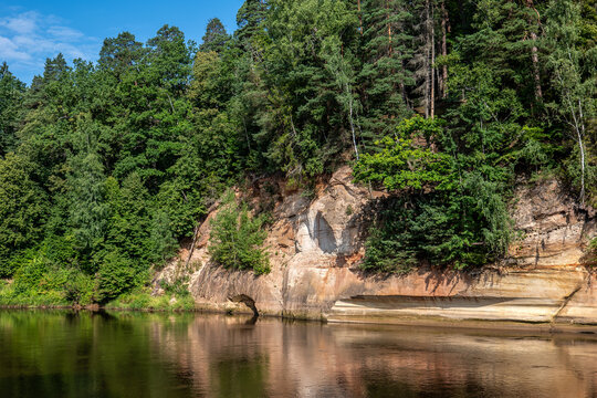 Layered Sandstone Cliffs Rise Above a Calm Forest River in Summer