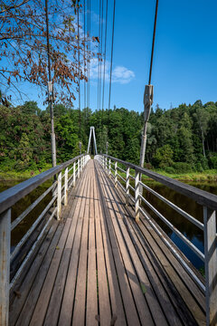 Wooden Suspension Bridge Crosses a Calm River Beneath a Clear Summer Sky