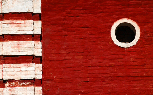 Massive vintage red brick wall with round window and column, old industrial architectural detail