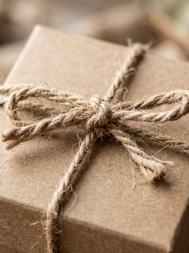 Close up of rustic cardboard gift parcel tied with hemp string knot
