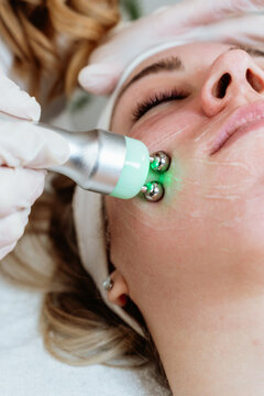 Cosmetologist using a modern cosmetic device for anti aging skin rejuvenation and toning on a client face in a wellness clinic.