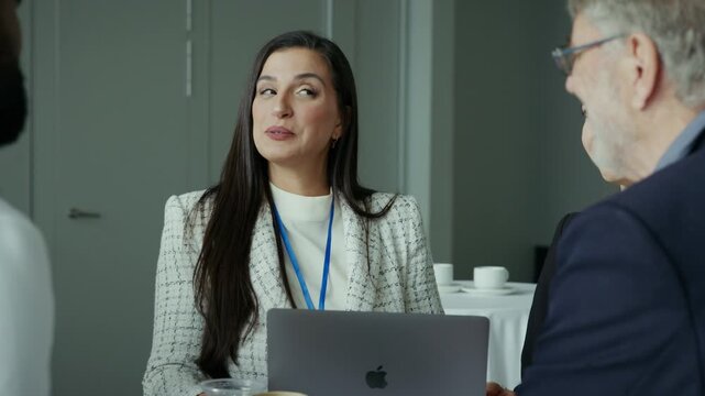 Professional business people are engaged in a lively group discussion during a conference. They are collaborating, sharing ideas, and networking, showcasing positive interactions at a corporate event.