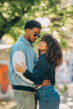 Happy young African American couple embracing outdoors, smiling affectionate man and woman looking into each other's eyes, romantic love and relationship concept