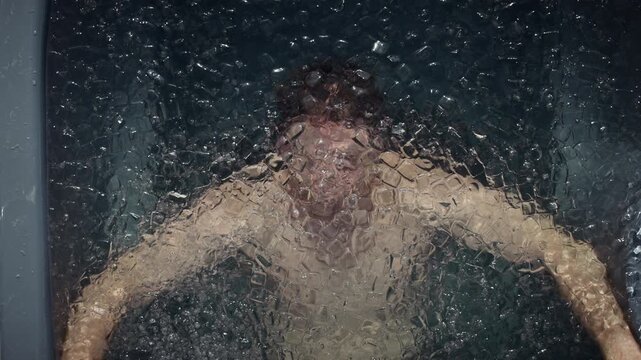 Man submerges into an outdoor ice bath with cold plunge focus for recovery