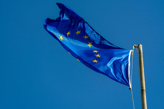 European Union flag waves in the sky on a clear day at a public location in Europe