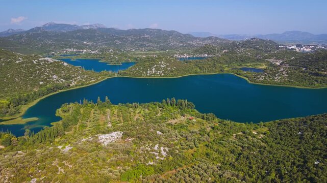 High angle aerial overview of the Bacina Lakes cluster surrounded by lush green hills near Ploce, Croatia