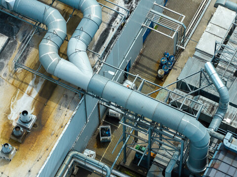 Aerial view of an advanced decorative packaging solutions factory featuring complex metallic ventilation ductwork and industrial piping on a flat roof in Poland.