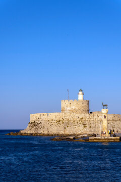The Colossus of Rhodes stands by the sea with lighthouse on the island of Rhodes in Greece