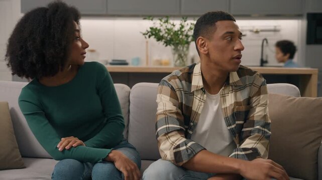 Stressed African American parents mother father with naughty little boy child son running in living room upset tired family bad behavior parenting difficulties irritated mom dad man woman kid indoors