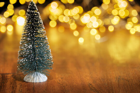 Christmas or New Year greeting card template with snow covered miniature Christmas trees and Christmas lights in the background. Xmas holidays atmosphere. Image with copy space and selective focus.	