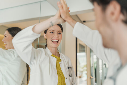 Female doctor gives a high five to a male colleague in a hospital