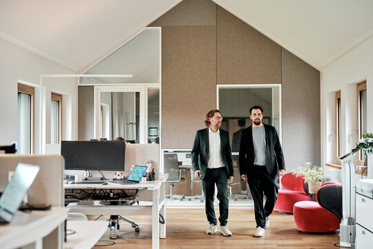 Businessman walking and talking with colleague in modern office