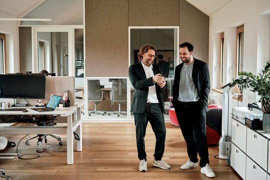 A businessman shows a smartphone to a colleague in a modern office