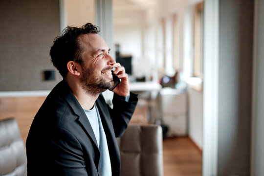 Happy businessman is calling on a smartphone in the office
