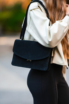 Woman carrying a bag, in outdoor blurred background, with woman, bag, from a side view of woman from behind perspective, with black, white accents, and casual everyday style mood.