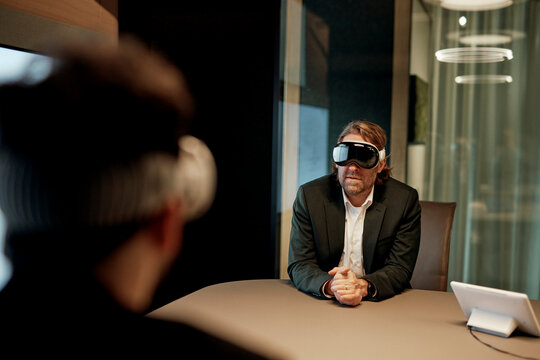 Two businessmen wear virtual reality headsets in a smart office