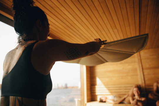 Sauna master leads nordic ritual with relaxing guest in sauna