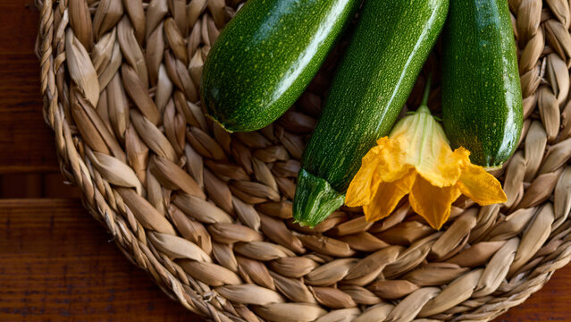 Freshly picked zucchini and blooming flower on a woven basket