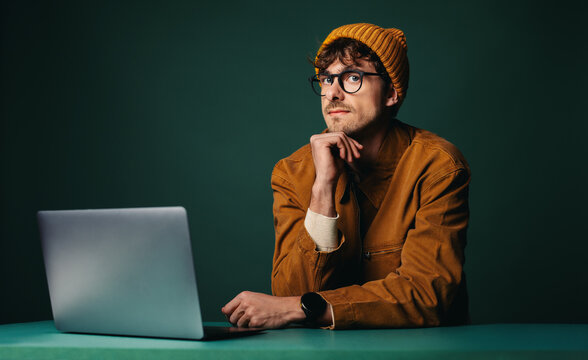 Thinking through work, the man uses a laptop in a studio workspace