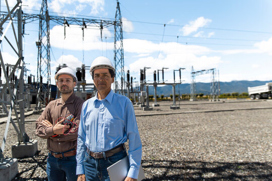 Male engineer and technician stand at an outdoor substation in Loja