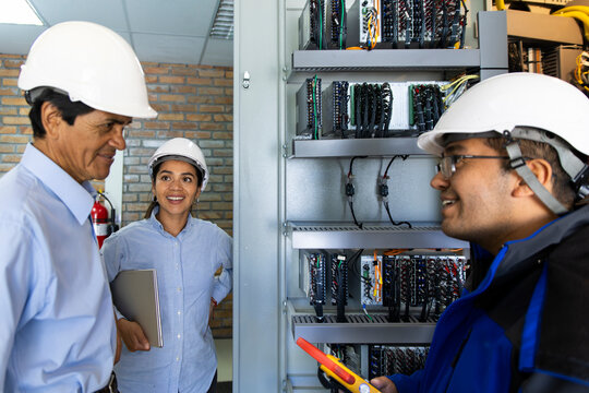 Professional engineers inspect electrical equipment indoors