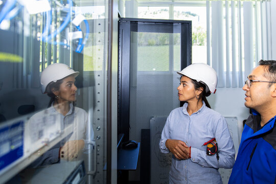 Engineer coworkers discuss an electrical control box indoors