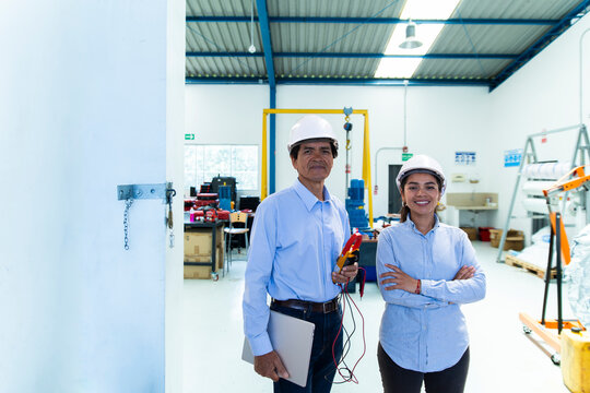 A man and woman hold equipment inside a wind farm workshop