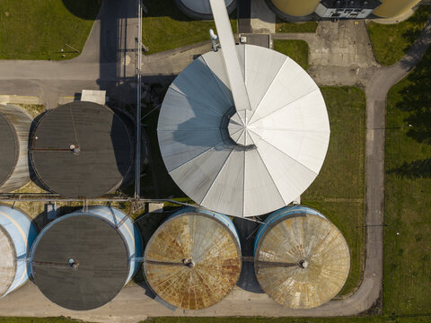 Aerial view of industrial sugar silos with metallic roofs and connecting walkways in Poland.