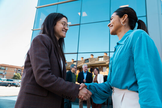 Smiling businesswomen are shaking hands during an outdoor meeting