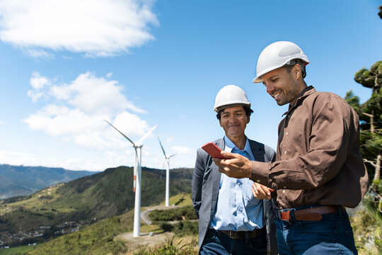 An engineer uses a smartphone near a wind turbine in Loja Ecuador